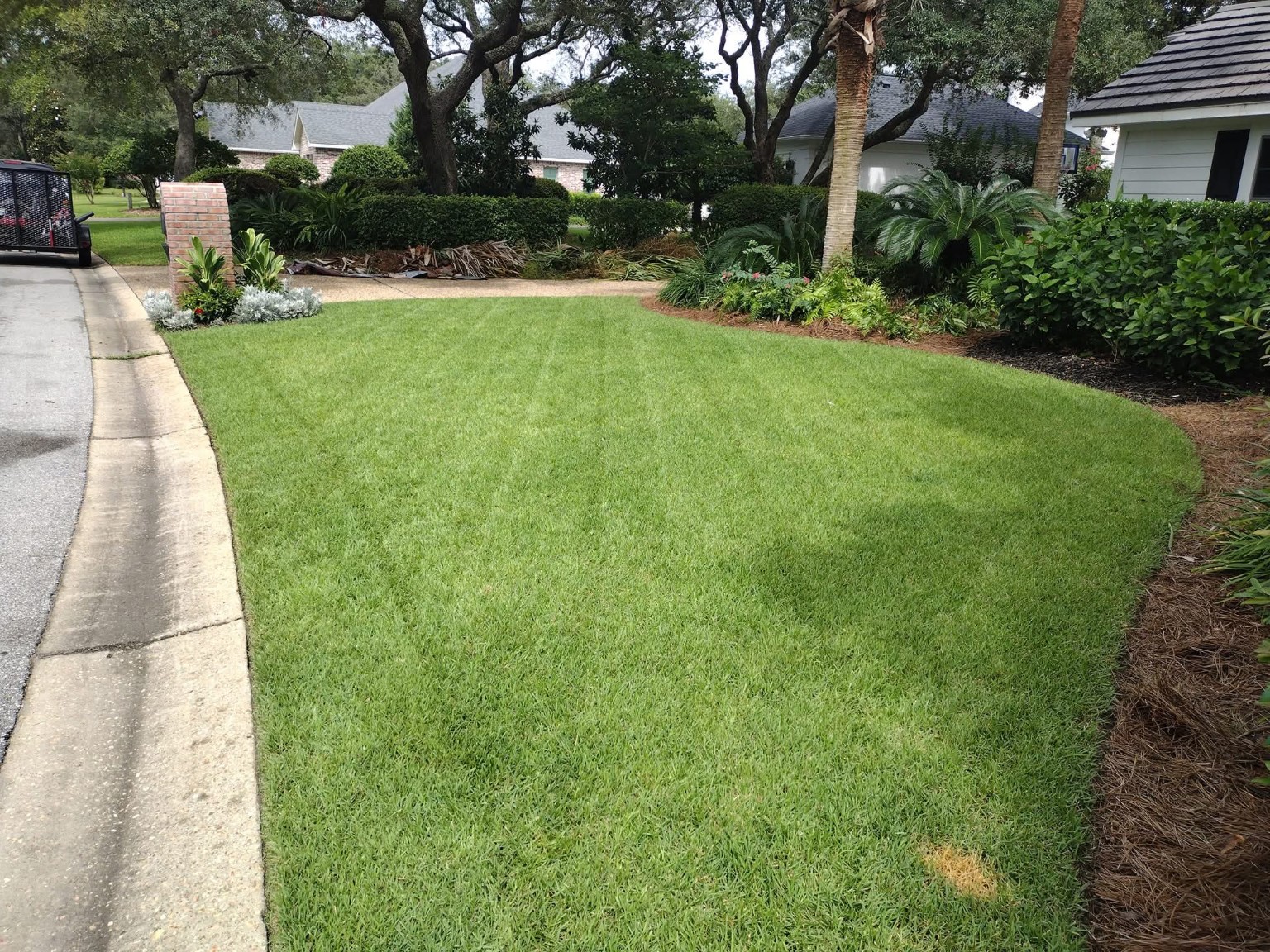 Actual Ohana Quality Services finished lawn maintenance beside landscaped beds